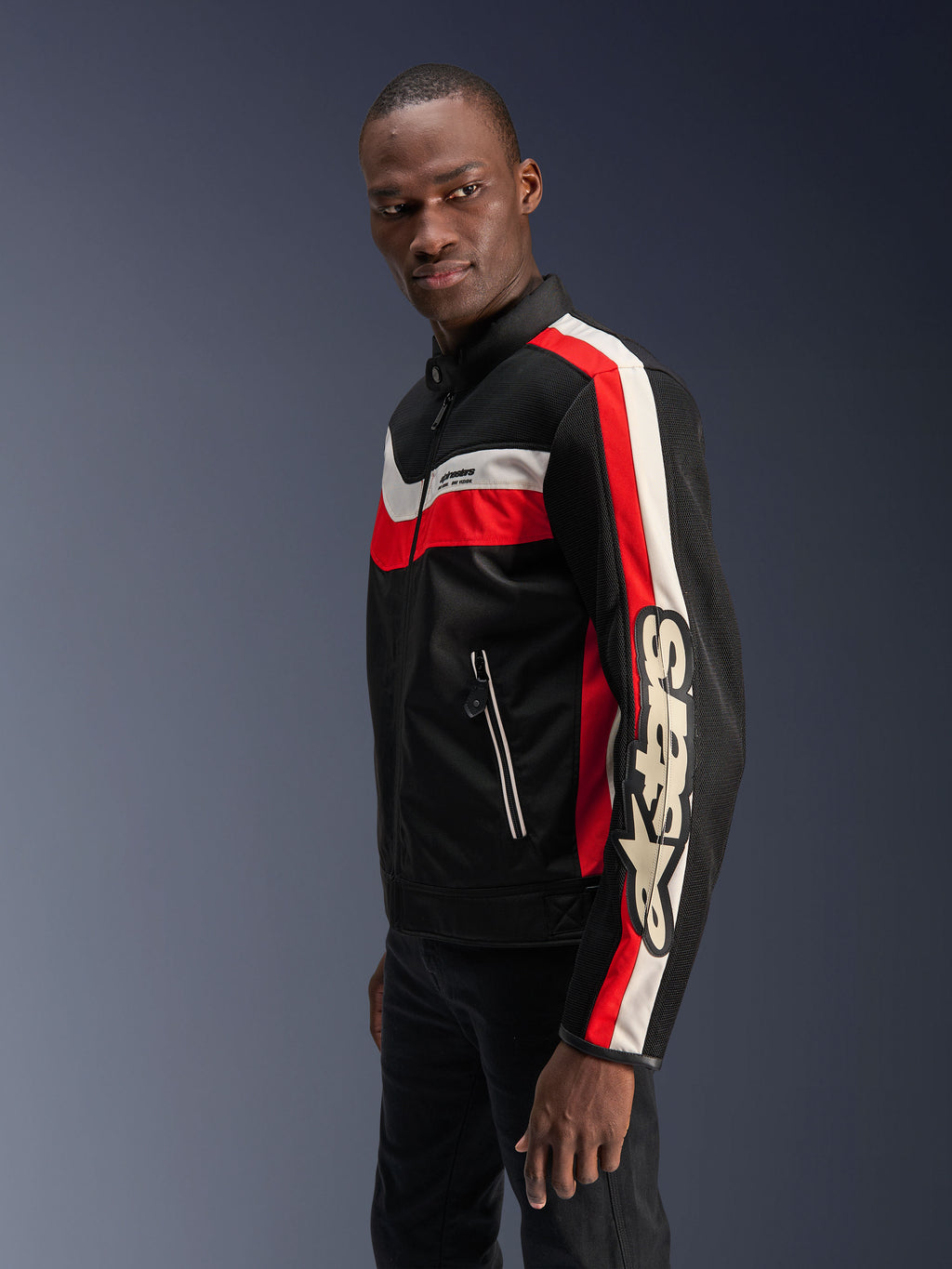 Mannequin homme portant la veste Alpinestars T-Dyno Air en Noir, Rouge Éclatant et Écru, veste de moto en textile d'inspiration vintage avec panneaux en maille 3D, rayures rouges et blanc cassé audacieuses, et logo Alpinestars distinctif sur la manche.