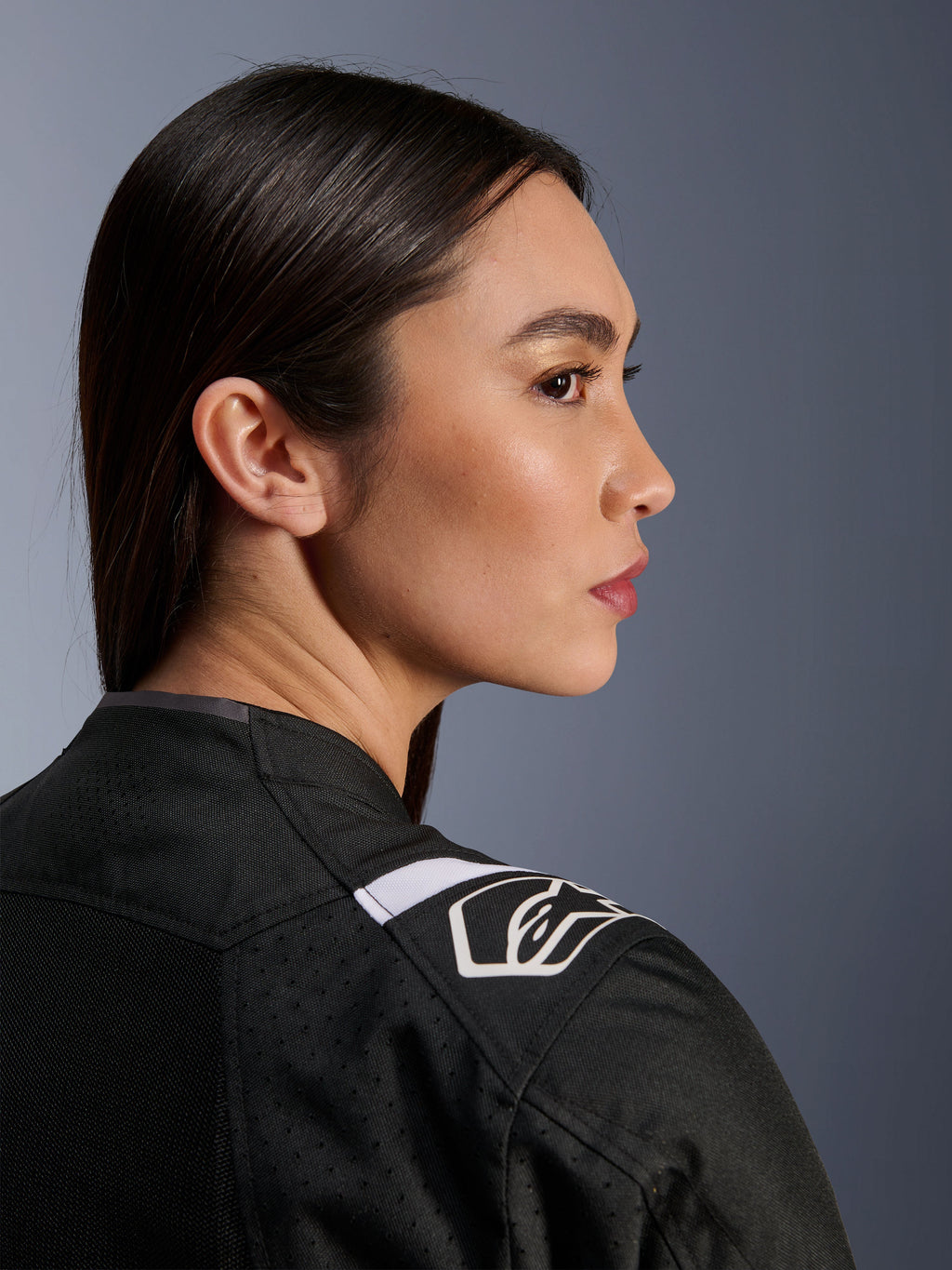 Vue de profil d'une femme portant la veste Alpinestars Stella T-Sps Air V2 en noir et blanc, gros plan sur l'épaule avec un logo Alpinestars blanc et une construction en tissu mesh pour la ventilation.