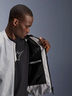 Modèle portant la veste Alpinestars C-1 Air argentée, ouvrant le devant pour révéler la doublure intérieure en mesh technique noir et une poche intérieure imperméable zippée.