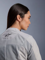 Femme portant la veste Alpinestars Stella C-1 Air en Silver, vue rapprochée de profil et de dos montrant le logo Alpinestars noir, les panneaux de ventilation en maille technique et un design de moto urbain épuré et contemporain.
