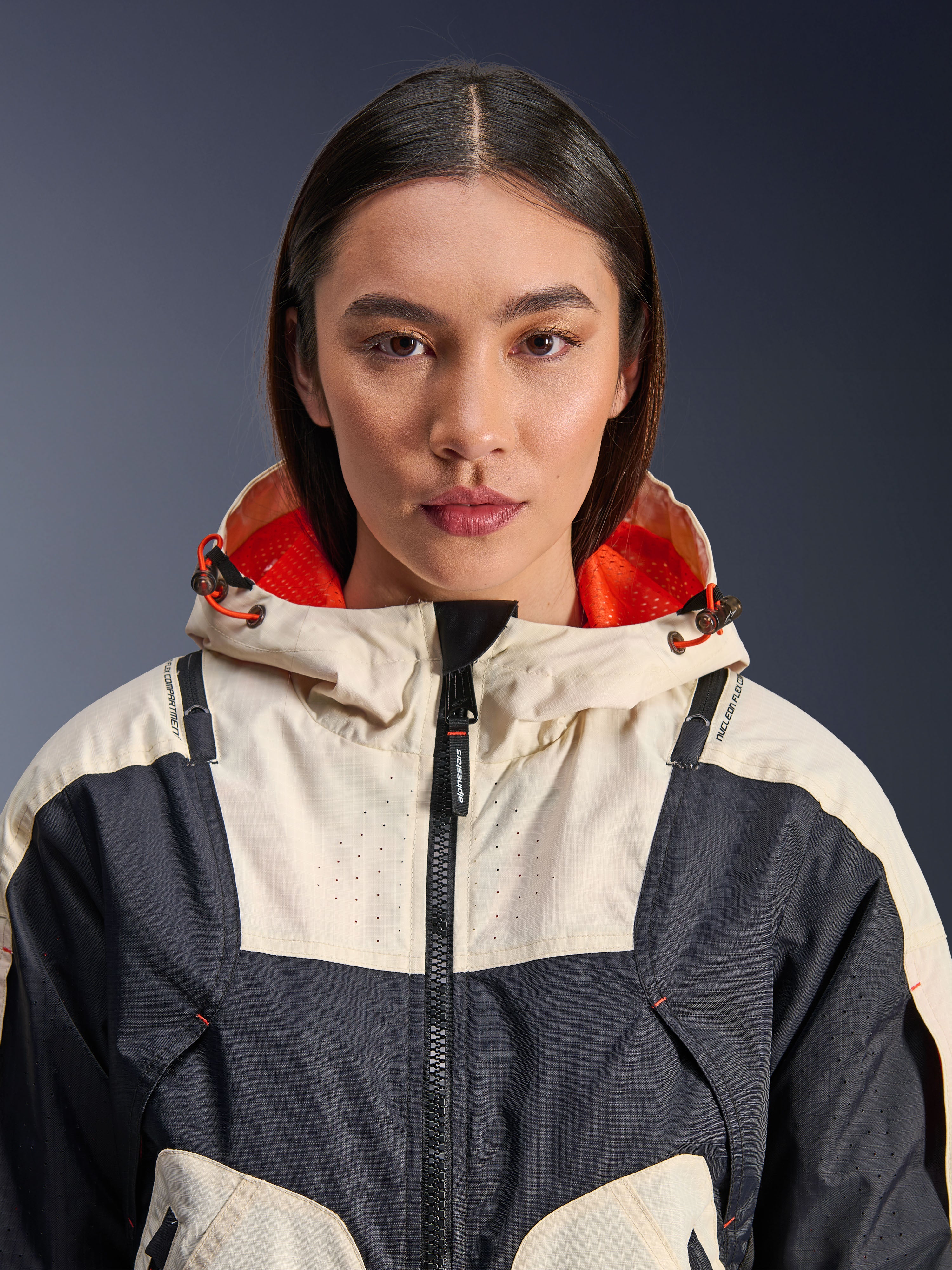 Veste Alpinestars Molly Air, veste de moto en textile pour femme, coloris Black Almond, vue rapprochée de face d'un mannequin portant la veste, design à empiècements crème et noir, capuche avec doublure en maille orange vif, détails perforés au laser sur la poitrine