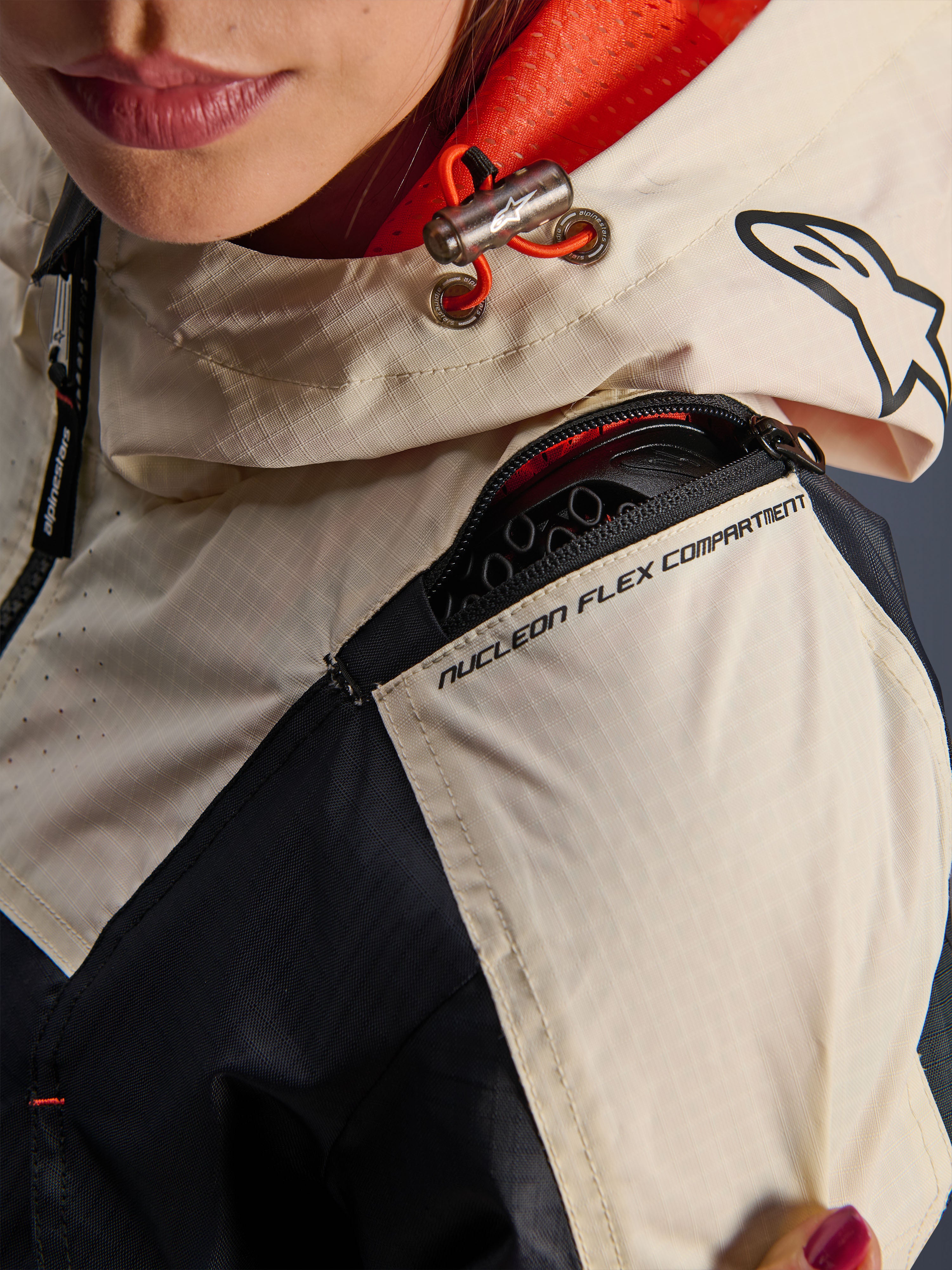 Veste Alpinestars Molly Air, veste de moto pour femme, Black Almond, vue rapprochée de l'épaule montrant la fermeture éclair du compartiment Nucleon Flex, le tissu ripstop et la doublure en maille orange à l'intérieur de la capuche