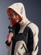 Veste Alpinestars Molly Air en Black Almond, portée par un mannequin femme avec la capuche relevée, présentant un design color-block crème et noir, une doublure en mesh orange vif et des éléments de design urbain technique incluant un logo étoile et des détails de zips.