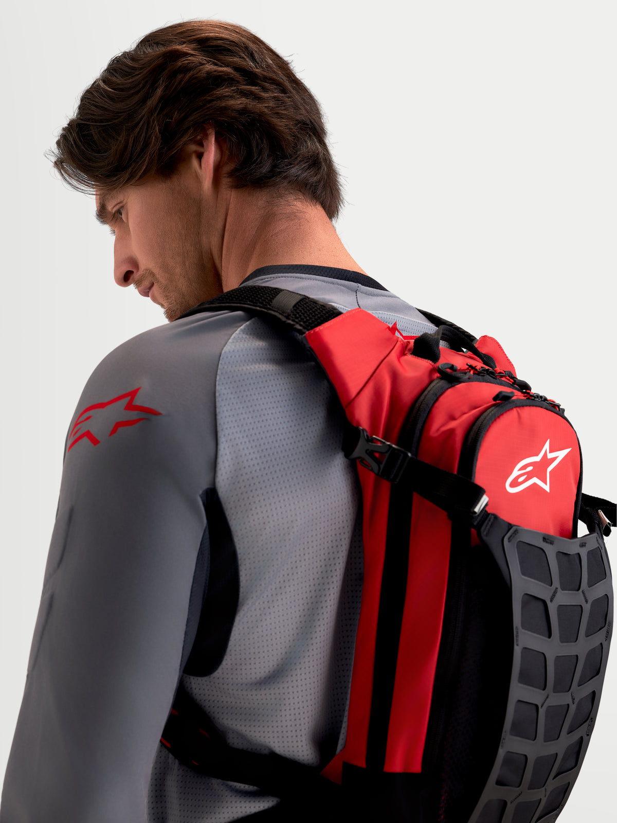 Sac à dos Alpinestars Sac À Dos AT-9, sac à dos de motocross pour homme, rouge et noir, porté par un modèle, avec bretelles rembourrées et rangement organisé pour les essentiels de la piste