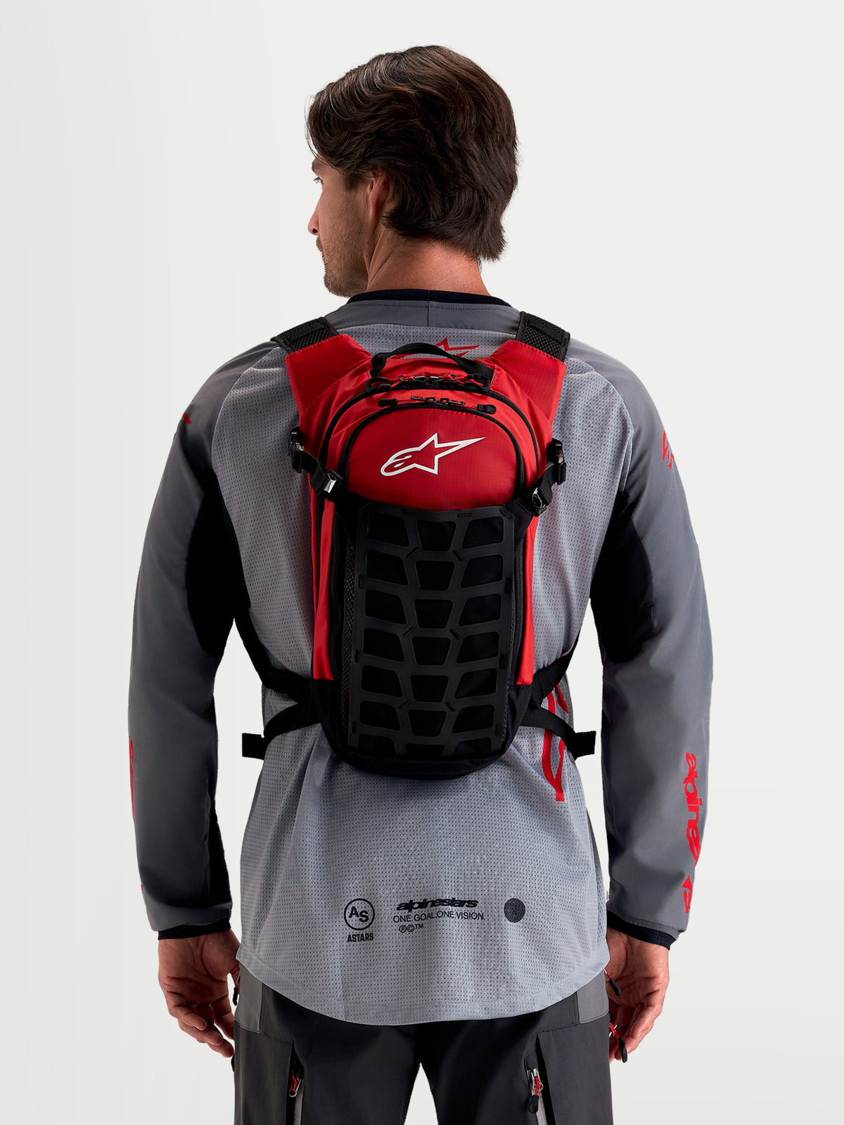 Sac à dos Alpinestars Sac À Dos AT-9, sac à dos de motocross noir et rouge, porté de dos par un modèle montrant la construction textile légère et le système de harnais rembourré