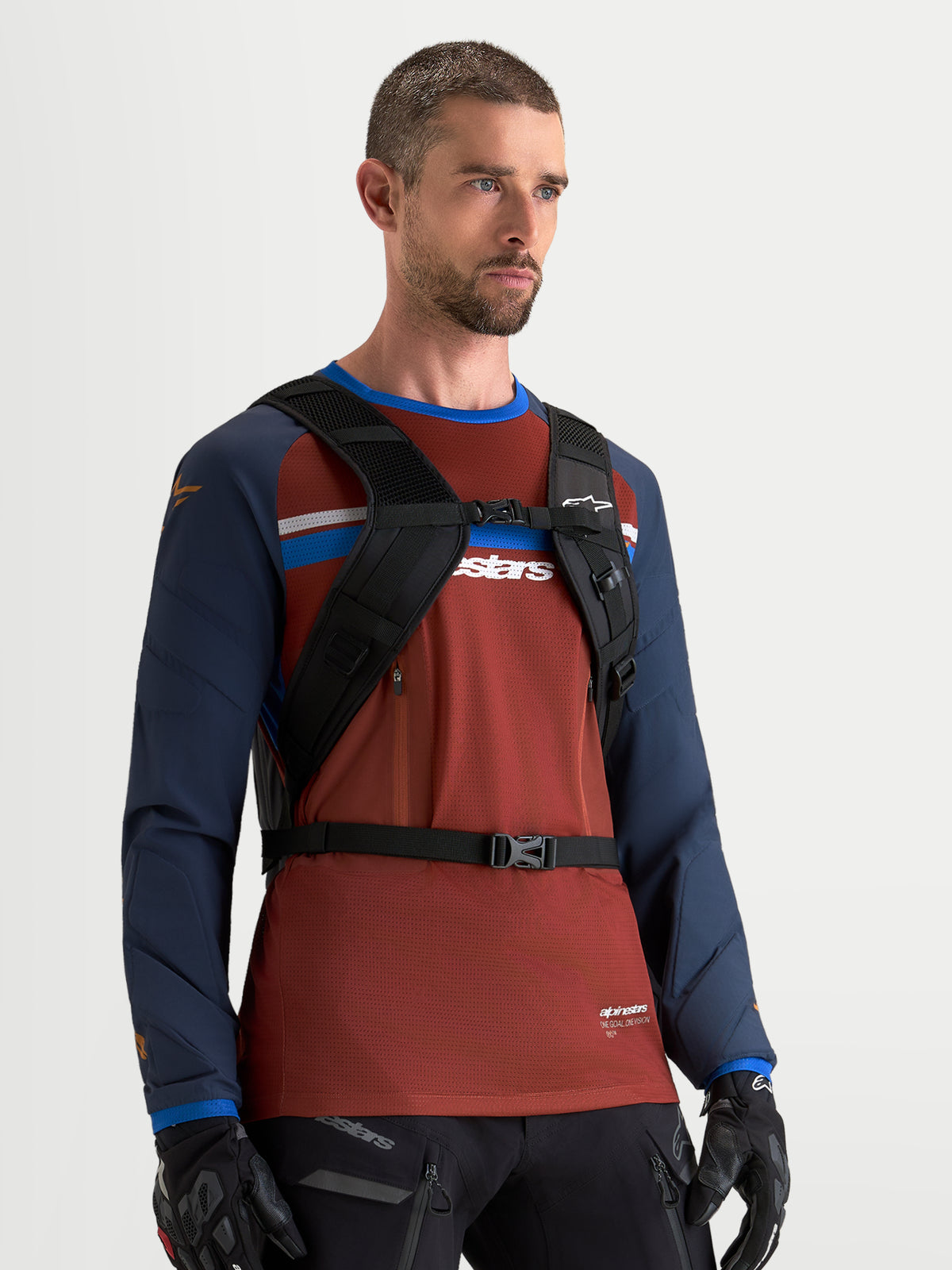 Sac à dos AT-9 Alpinestars, sac à dos de motocross noir, porté par un modèle masculin montrant le harnais d'épaule rembourré et le système de sangle de poitrine