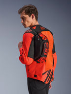 Sac banane Alpinestars MM93, noir avec rouge fluo et rouge vif, porté par un mannequin en bandoulière sur le dos par-dessus une veste de moto rouge et noire, avec logo MM93 et graphismes Marc Marquez