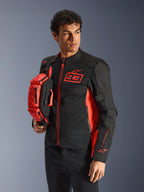 Sac banane Alpinestars MM93, rouge fluo et noir, tenu par un mannequin portant une veste de moto assortie noire et rouge, doté de plusieurs compartiments zippés et du marquage Marc Marquez, équipement pratique pour la conduite sportive