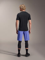 Alpinestars A-Aria Switch Short Sleeve Jersey, Black MTB Jersey, seen from the back, paired with blue mountain bike shorts and black leg protection, performance cycling gear for trail riding