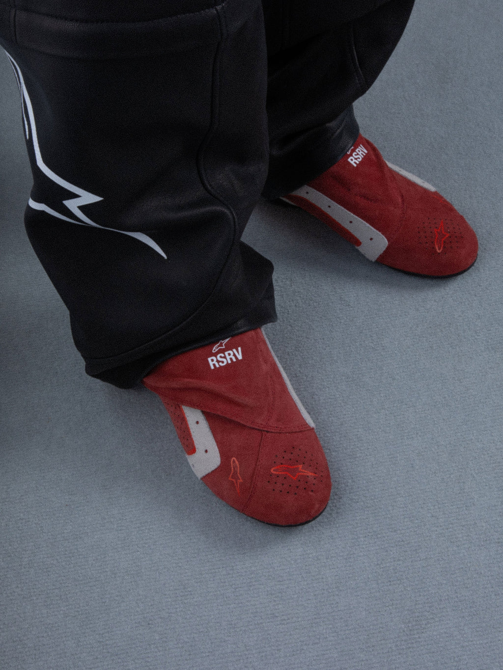 Alpinestars RSRV Starline Shoes, chaussons rouges avec détails blancs et gris, texte "RSRV", texture douce, portés avec pantalon noir à logo blanc