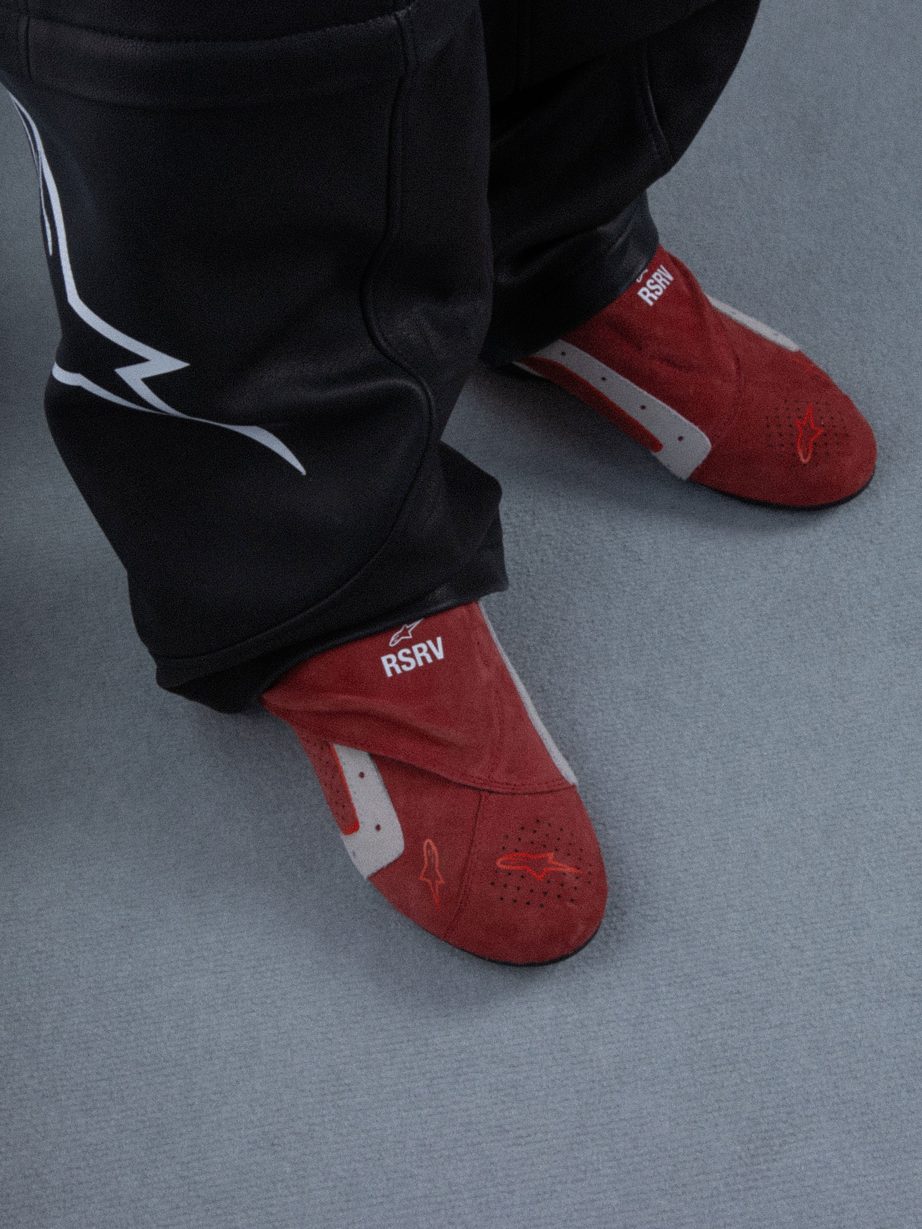 Alpinestars RSRV Starline Shoes, chaussons rouges avec détails blancs et gris, texte "RSRV", texture douce, portés avec pantalon noir à logo blanc