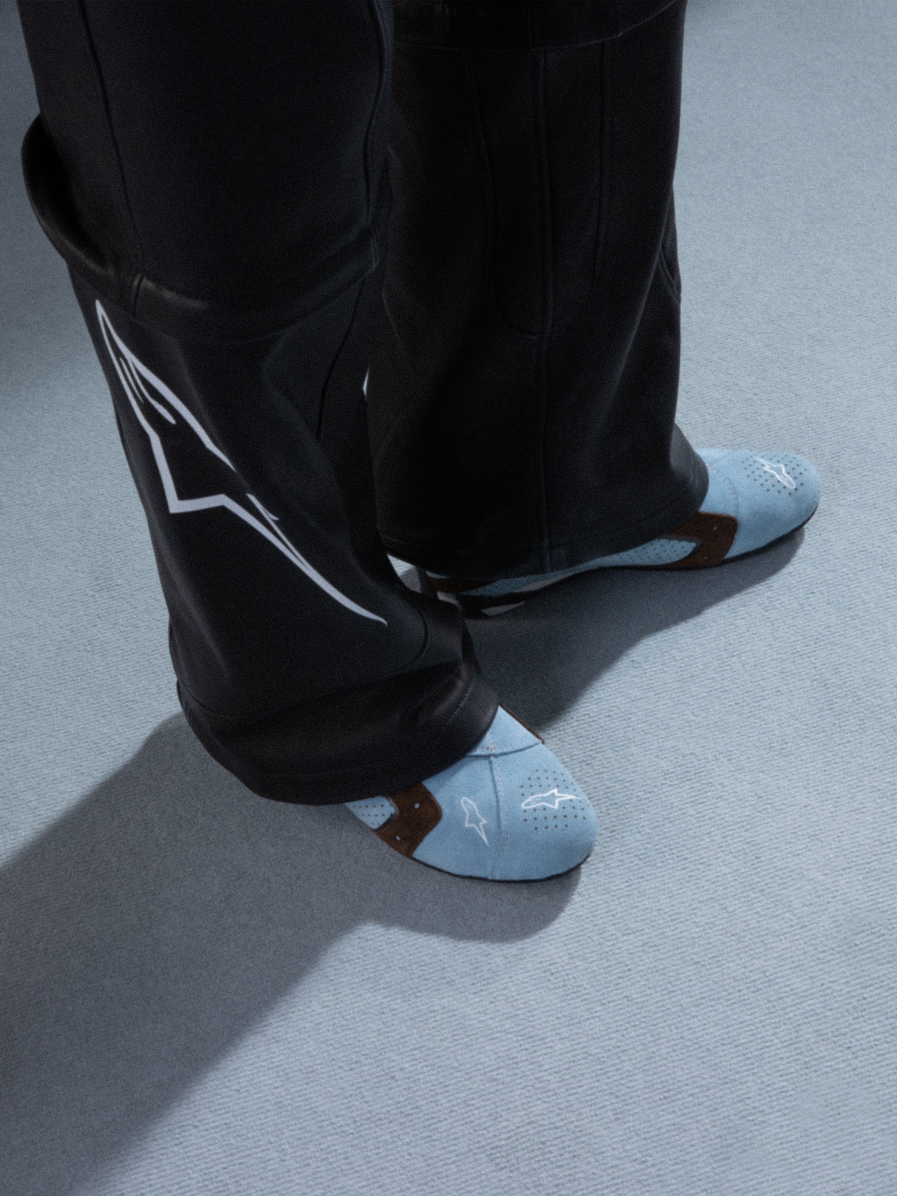 Alpinestars RSRV Starline Shoes, chaussures casual premium, bleu clair avec perforations et accents marron, logo blanc Alpinestars, portées avec pantalon en cuir noir à motifs blancs