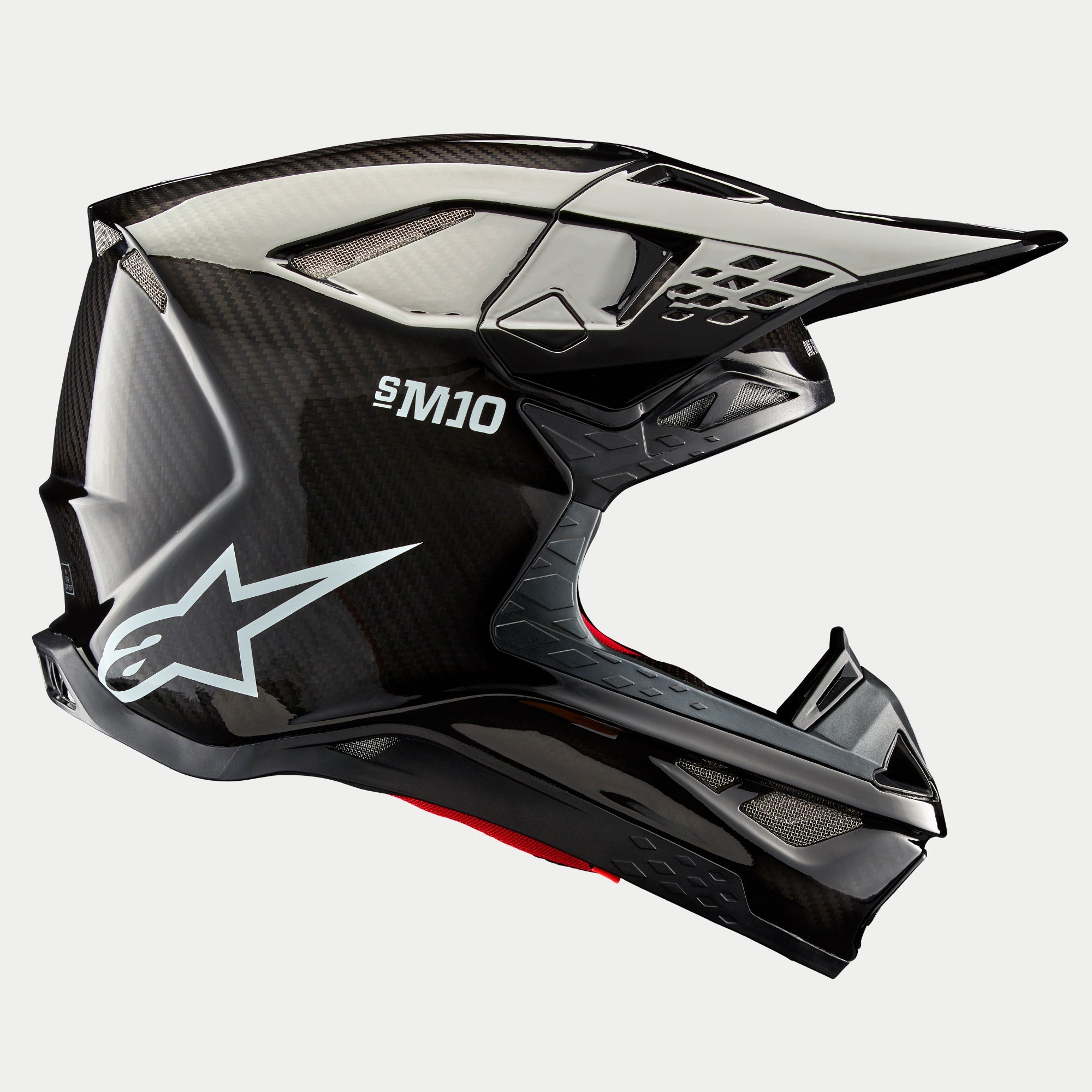 Alpinestars Supertech M10 Solid Helmet, Black Glossy Carbon, Motocross Helmet, side profile view showing glossy carbon fiber weave, S-M10 branding, white Alpinestars star logo, aerodynamic design with peak visor and ventilation ports