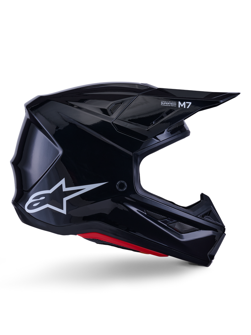Casque Alpinestars S-M7 Solid, casque de motocross, noir brillant avec logo étoile blanc et accents rouges, profil latéral présentant un design aérodynamique avec des aérations en maille angulaires et le marquage Supertech M7 sur la visière