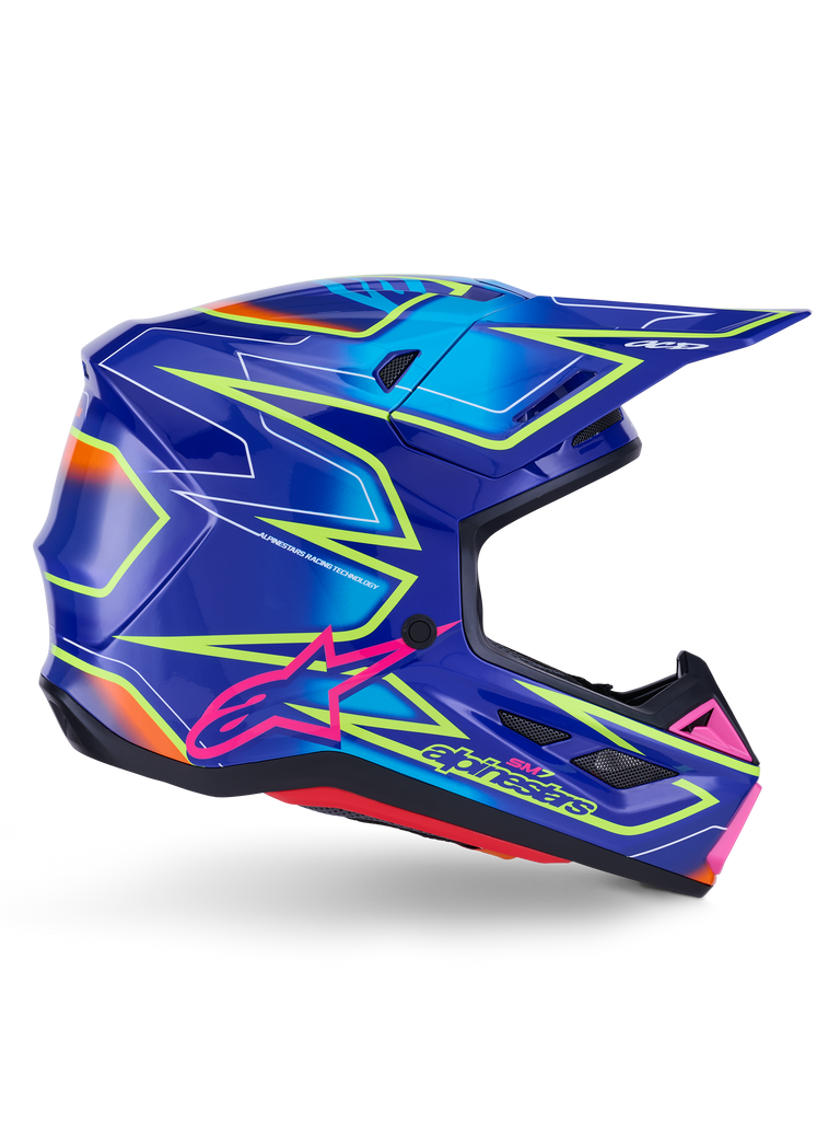 Casque Alpinestars S-M7 Cast, casque de motocross, bleu, rose et jaune fluo brillant, vue de profil avec motifs géométriques audacieux, logo Alpinestars rose et coque aérodynamique ventilée.