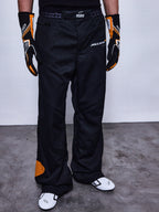 Alpinestars RSRV Arena Suit Pants, pantalon de course noir avec logos McLaren et Alpinestars, détails orange, porté avec gants noirs et orange et chaussures de course blanches
