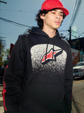 Sweat à capuche Alpinestars Obsessed, polaire noire à enfiler, graphisme blanc avec dégradé MX sur la poitrine et logo étoile rouge, logos rouges sur les manches, streetwear décontracté d'inspiration sport automobile porté dans un environnement urbain.