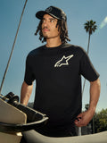 T-shirt Alpinestars One Oversized CSF, t-shirt à manches courtes, noir avec logo Astars blanc, porté par un homme portant une casquette trucker noire, cadre lifestyle extérieur avec palmiers et moto, streetwear décontracté.