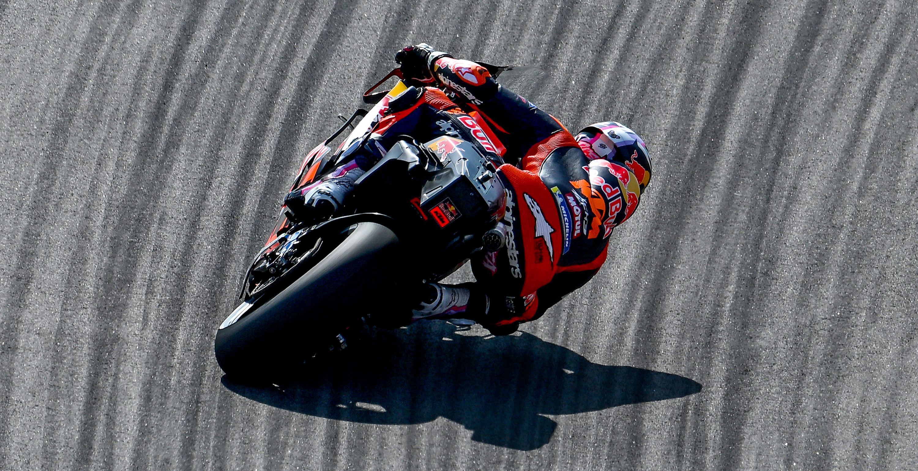 Enea Bastianini in red and blue Alpinestars racing suit leaning into a turn on a racetrack