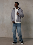 Alpinestars Essentials Ageless Zip Hoodie, Silver, streetwear décontracté, sweat à capuche zippé en polaire avec un petit logo noir sur la poitrine, porté par un mannequin avec un t-shirt blanc et un jean bleu, coupe lifestyle décontractée