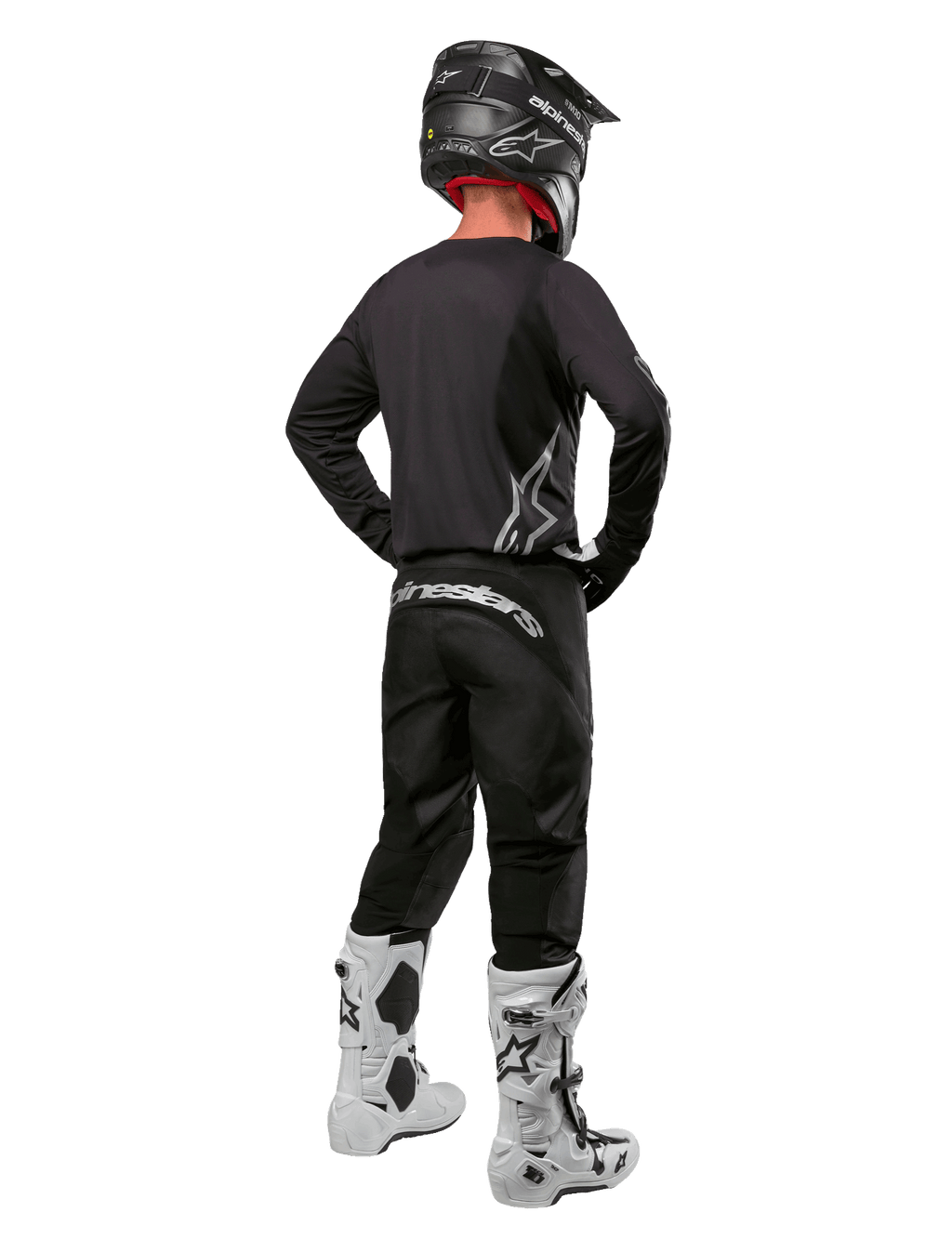 Ensemble d'équipement Alpinestars 2024 Fluid Graphite, pilote de motocross vu de dos, maillot et pantalon gris graphite avec logos Alpinestars argentés, casque noir et bottes de motocross blanches, tenue à coupe athlétique pour la conduite tout-terrain