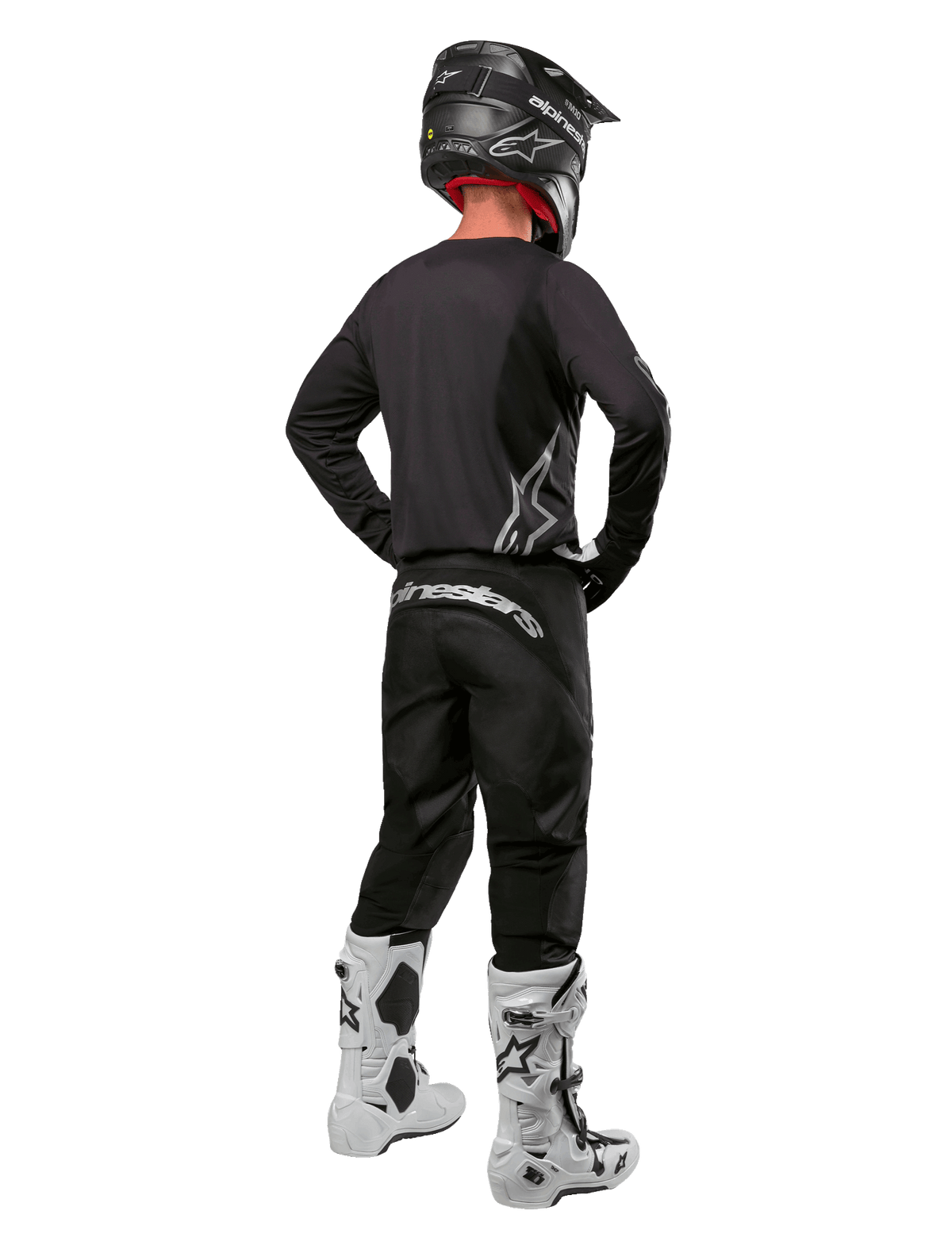 Ensemble d'équipement Alpinestars 2024 Fluid Graphite, pilote de motocross vu de dos, maillot et pantalon gris graphite avec logos Alpinestars argentés, casque noir et bottes de motocross blanches, tenue à coupe athlétique pour la conduite tout-terrain