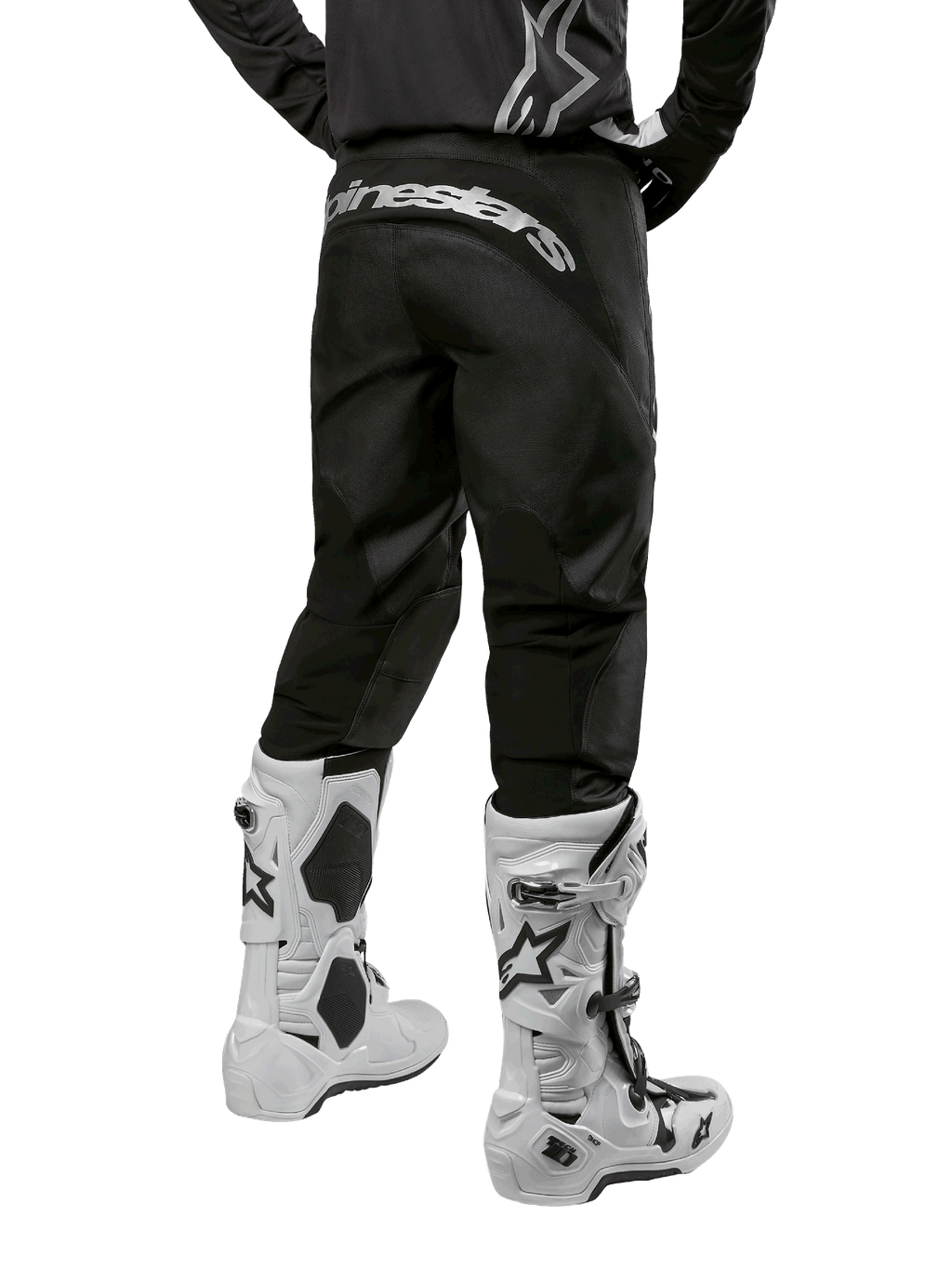 Pantalon Alpinestars Fluid Graphite 2024, pantalon de motocross, noir et argent, vue arrière montrant le marquage Alpinestars argenté sur l'empiècement arrière, porté avec des bottes de motocross blanches et noires, conception en textile durable pour le tout-terrain