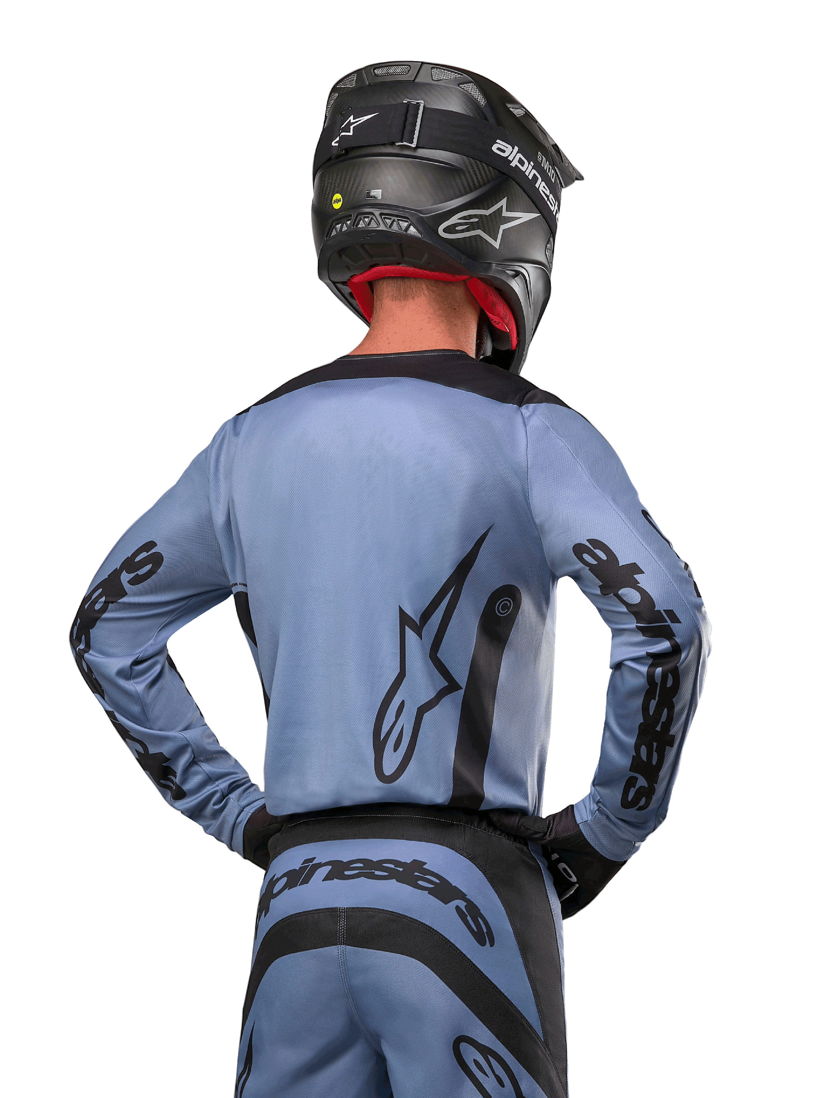 Maillot Alpinestars 2024 Fluid Lurv, maillot de motocross, bleu clair et noir, vue arrière du pilote montrant le grand logo étoilé et le marquage sur les manches, porté avec un casque noir et un pantalon tout-terrain assorti, équipement de course professionnel