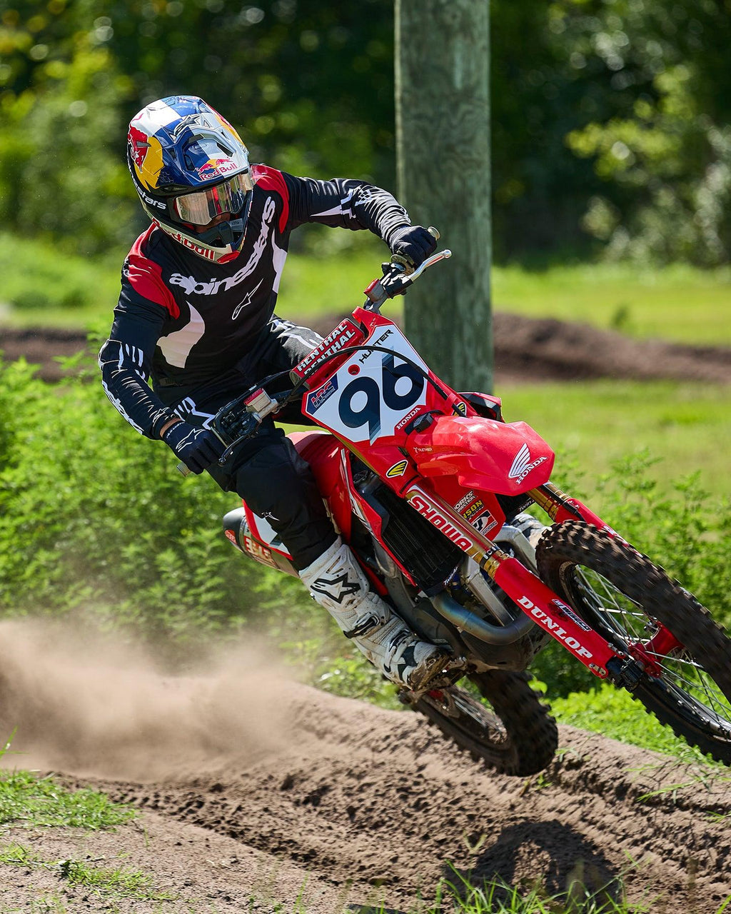 Alpinestars Fluid Haul 2025, tenue de motocross noire et blanche, pilote 96 sur moto Honda rouge en virage poussiéreux.