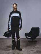 Alpinestars RSRV Track Jacket, veste de survêtement noire et grise avec logo étoile, portée avec un casque noir assorti, style streetwear premium inspiré du sport automobile