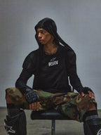 T-shirt Alpinestars RSRV Nucleon SS, noir avec logo RSRV blanc, porté avec pantalon camouflage et équipement de protection tactique