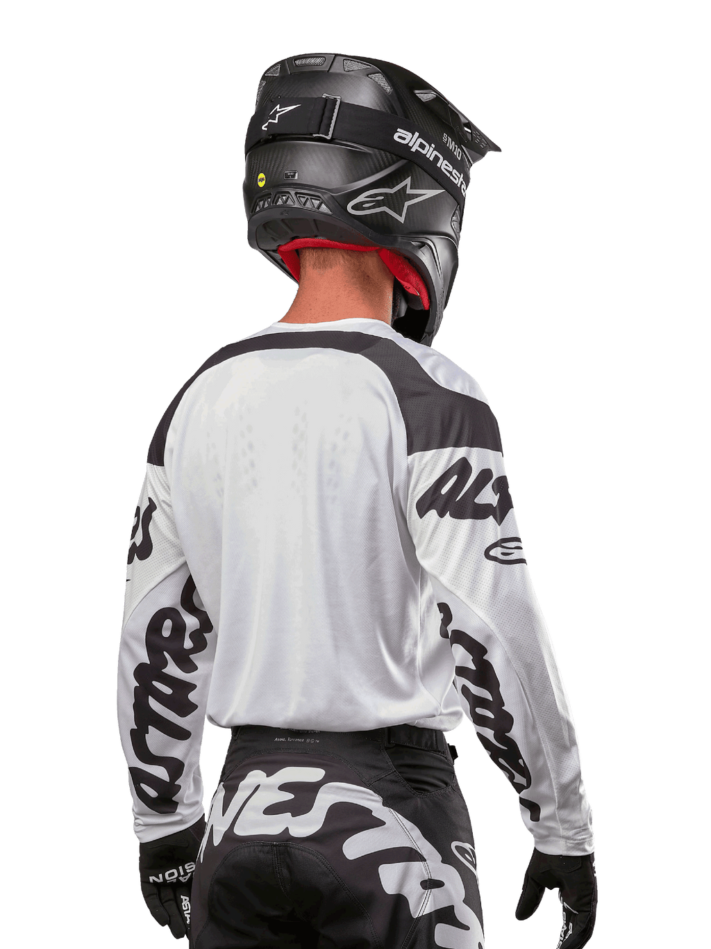 Maillot Alpinestars Racer Hana 2024, blanc et noir, vue de dos montrant la coupe ergonomique et le marquage imposant sur les manches, associé à un casque de motocross noir et un pantalon noir et blanc assorti, équipement de course haute performance pour la conduite tout-terrain
