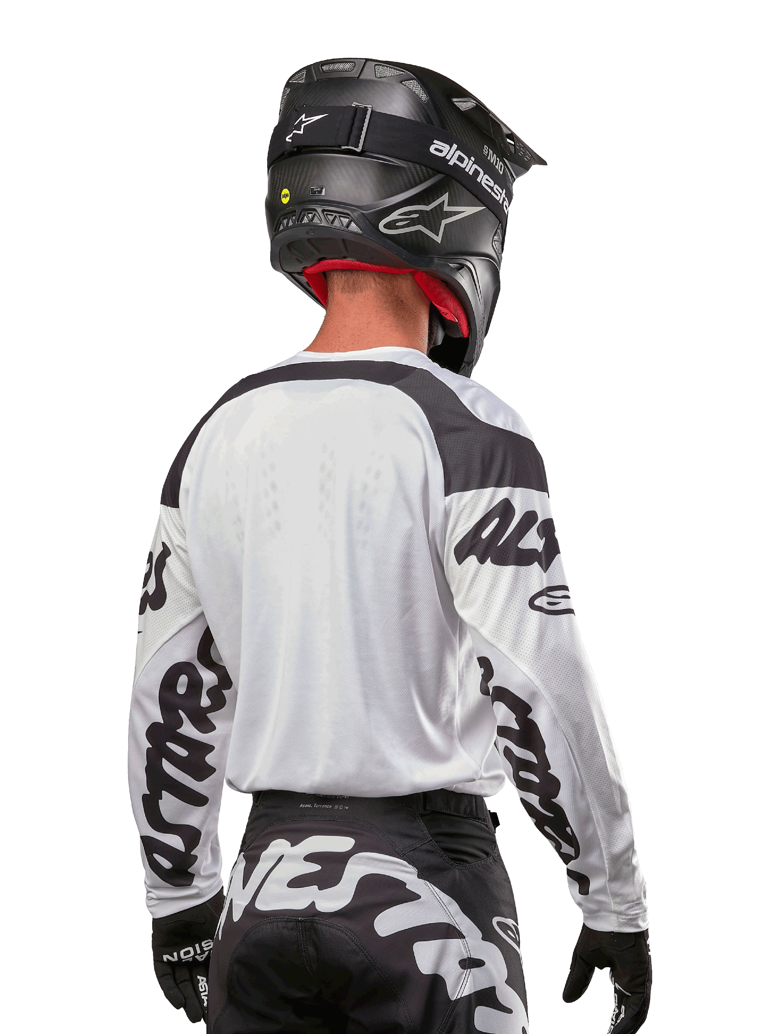 Maillot Alpinestars Racer Hana 2024, blanc et noir, vue de dos montrant la coupe ergonomique et le marquage imposant sur les manches, associé à un casque de motocross noir et un pantalon noir et blanc assorti, équipement de course haute performance pour la conduite tout-terrain