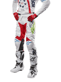 Alpinestars Pantalon Racer Hana 2024, pantalon de motocross, blanc avec accents rouge, bleu et vert citron, doté d'un design protecteur avec empiècements en cuir aux genoux, porté avec maillot assorti, gants rouges et bottes blanches à boucles, tenue de sport mécanique