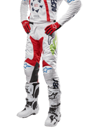Alpinestars Pantalon Racer Hana 2024, pantalon de motocross, blanc avec accents rouge, bleu et vert citron, doté d'un design protecteur avec empiècements en cuir aux genoux, porté avec maillot assorti, gants rouges et bottes blanches à boucles, tenue de sport mécanique