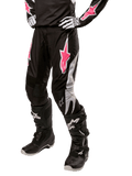 Alpinestars Stella Fluid Pant 2024 pour femme, pantalon de motocross, noir et blanc avec des touches de rose, porté avec un équipement de protection assorti incluant bottes et gants, tissu flexible et durable pour la conduite tout-terrain