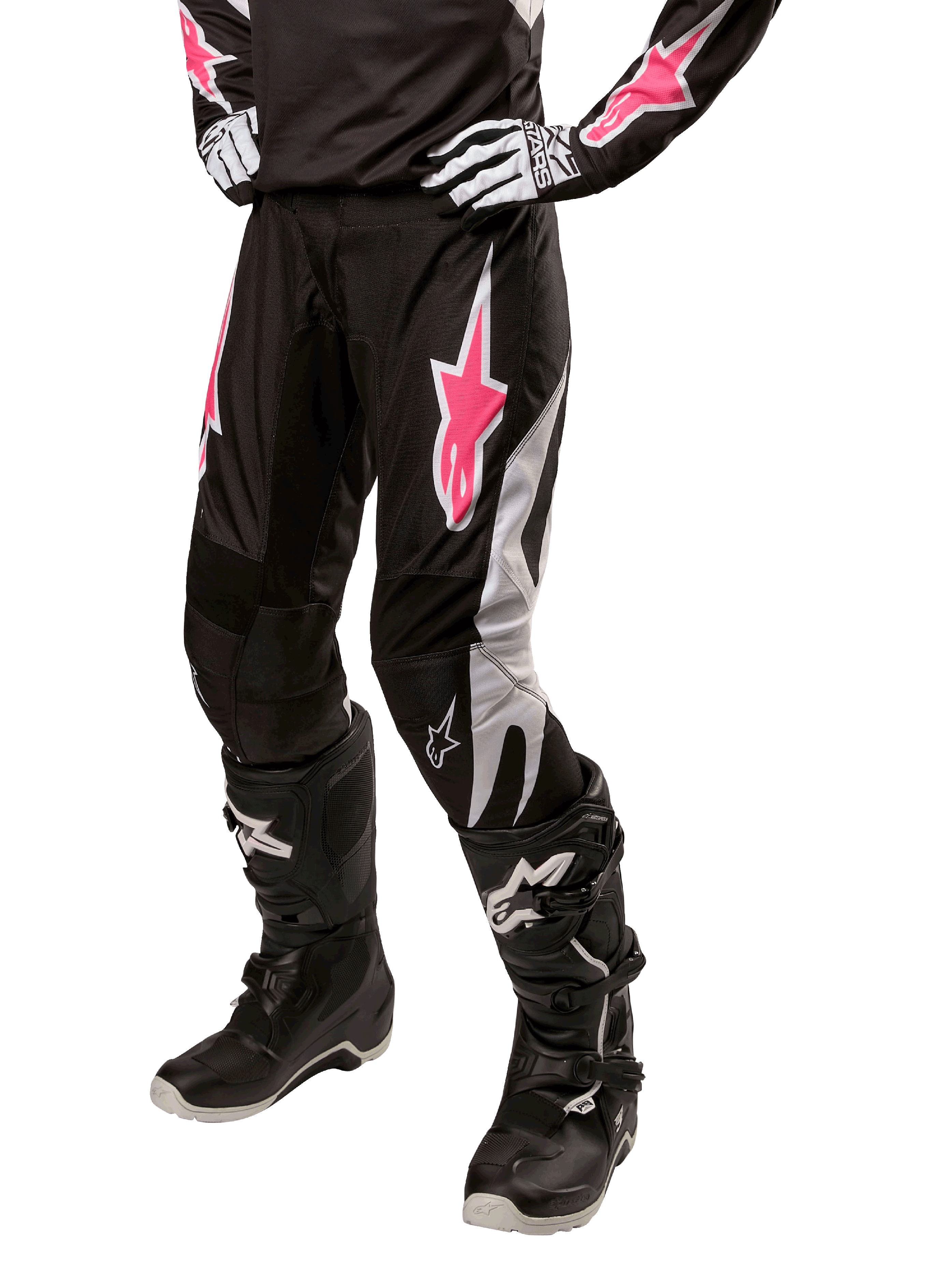Alpinestars Stella Fluid Pant 2024 pour femme, pantalon de motocross, noir et blanc avec des touches de rose, porté avec un équipement de protection assorti incluant bottes et gants, tissu flexible et durable pour la conduite tout-terrain
