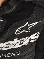 Gros plan sur la combinaison en cuir 2 pièces Alpinestars Stella GP-R7 en noir, avec des panneaux en cuir perforé, un grand logo Alpinestars blanc sur la poitrine et des sections en tissu extensible respirant.