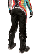 Pantalon femme Alpinestars Stella Techstar 2024, pantalon de motocross, noir multicolore, vue arrière présentant un marquage blanc imposant sur le fessier, porté avec des bottes Tech 3 noires et un maillot multicolore assorti, équipement de course tout-terrain professionnel