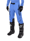 Alpinestars 2024 Supertech Dade Pants, Motocross Pants, Light Blue with black graphic logos, featuring ventilated perforations and a magnetic waist buckle, paired with black technical riding boots and gloves, professional off-road racing gear