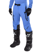 Alpinestars 2024 Supertech Dade Pants, Motocross Pants, Light Blue with black graphic logos, featuring ventilated perforations and a magnetic waist buckle, paired with black technical riding boots and gloves, professional off-road racing gear