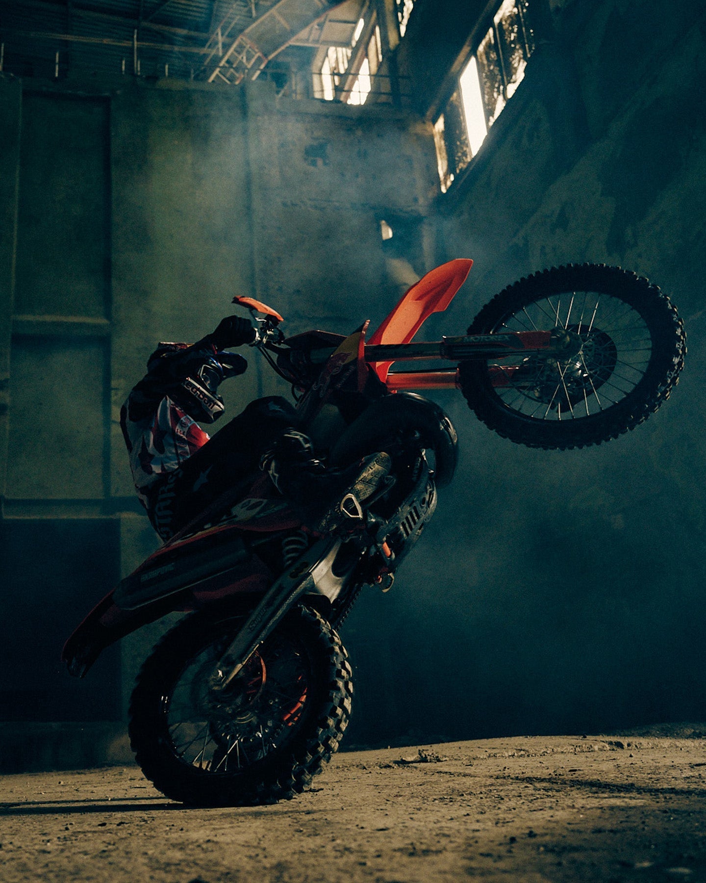 Alpinestars Limited Edition S-M7 Beast Coast Helmet in Light Gray and Hot Orange, worn by a motocross rider performing a wheelie.