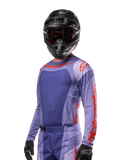 Maillot Alpinestars Techstar Ocuri 2024, maillot de motocross, violet et orange vif, à manches longues avec perforations découpées au laser pour la ventilation, coupe de course athlétique, porté avec un casque de motocross et des gants noirs