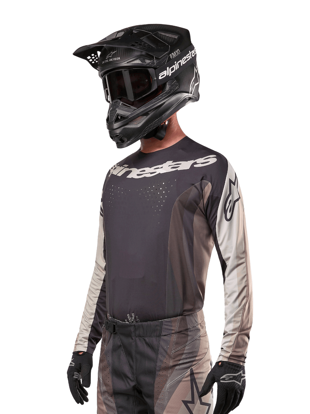 Maillot Alpinestars Techstar Pneuma 2024, maillot de motocross, sable foncé et gris fer, haut de performance à manches longues avec perforations au laser et logos blancs, porté avec un pantalon assorti et un casque noir, coupe athlétique pour le pilotage tout-terrain