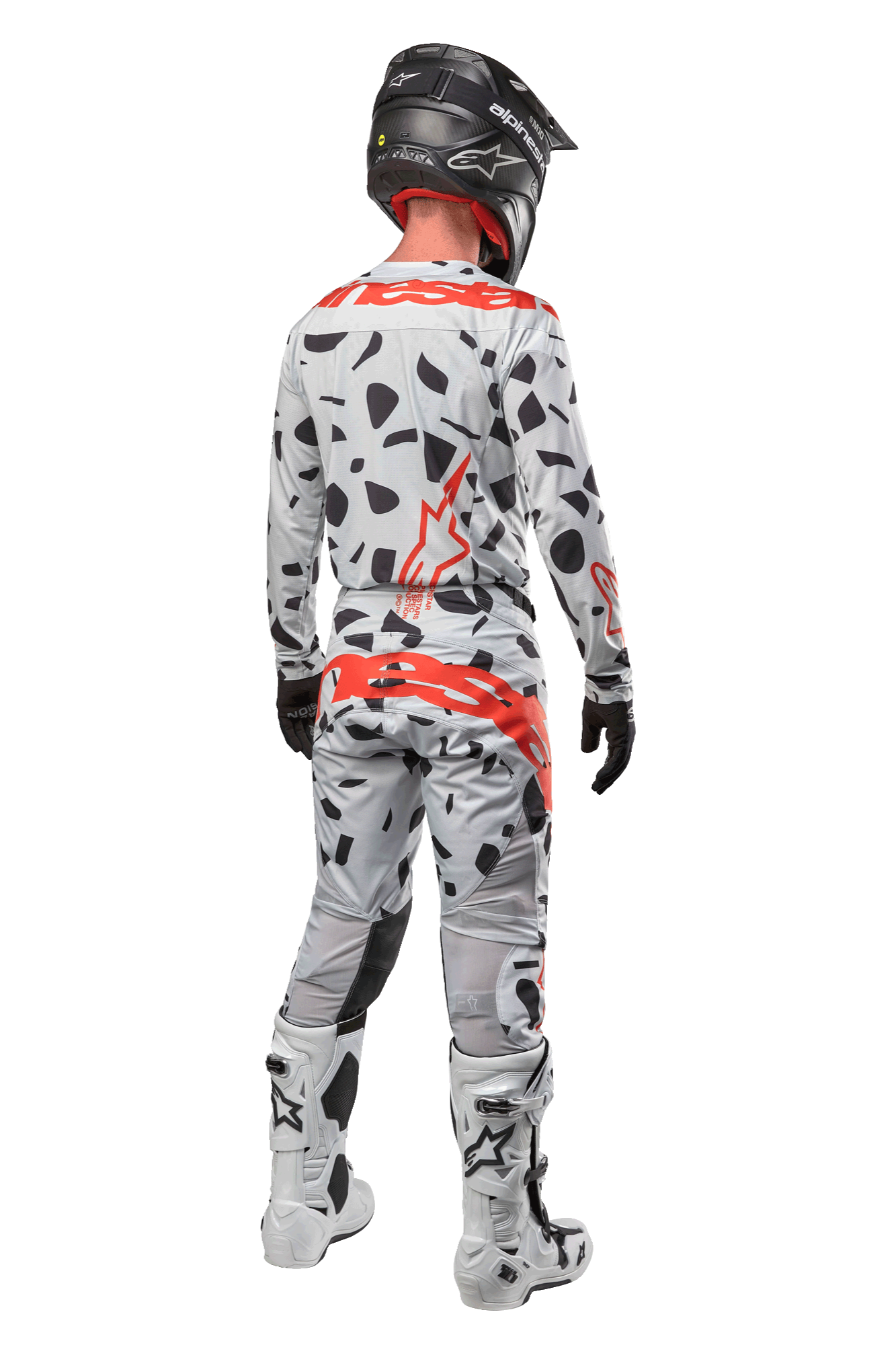 Motocross rider from the back wearing Alpinestars 2024 Techstar Rantera Pants, Haze Gray Camo with black spots and red logos, matching jersey, black helmet, and white boots, complete off-road racing outfit