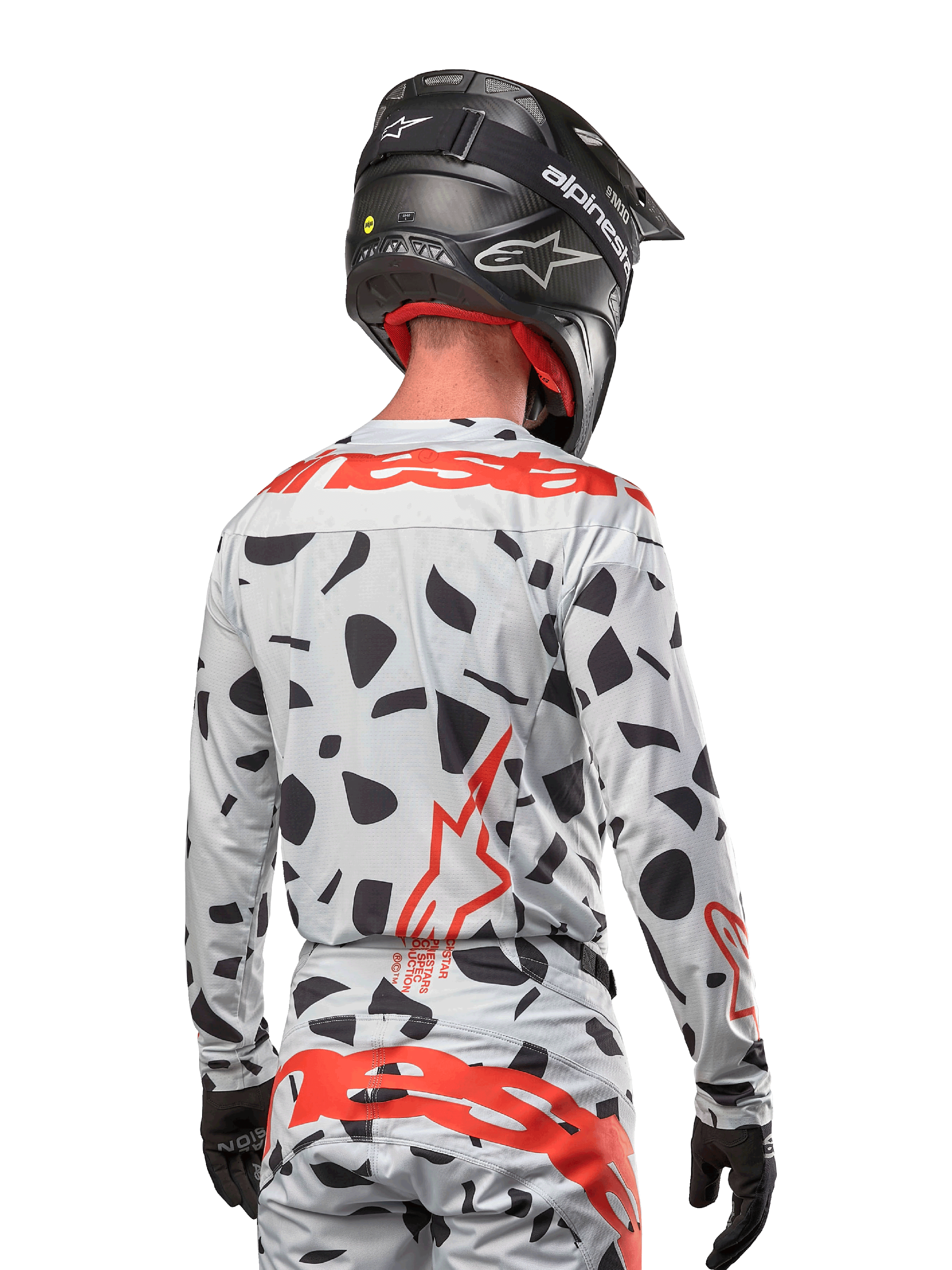 Motocross rider from the back wearing the Alpinestars 2024 Techstar Rantera Jersey in Haze Gray Camo, featuring a light gray base with black graphic spots and bold red Alpinestars logos on the back and shoulders, paired with matching pants and a black helmet.