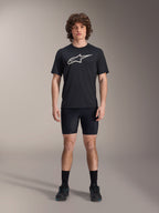 Short Liner Alpinestars A-Dura, sous-short de cyclisme noir, porté par un mannequin avec un t-shirt noir à logo Alpinestars et des chaussures de cyclisme noires, coupe ajustée pour la performance en VTT et le confort en selle