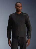 Mannequin homme portant la veste Alpinestars C-1 Air noire, une veste de moto contemporaine dotée de larges panneaux en maille technique et d'une fermeture éclair frontale intégrale, associée à un pantalon de moto noir assorti, esthétique urbaine et trajets quotidiens