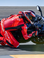 Combinaison en cuir Alpinestars GP Plus V4 Sprint 1 pièce, rouge fluo et blanche, prête pour Tech-Air®, sur un pilote en plein virage sur circuit.