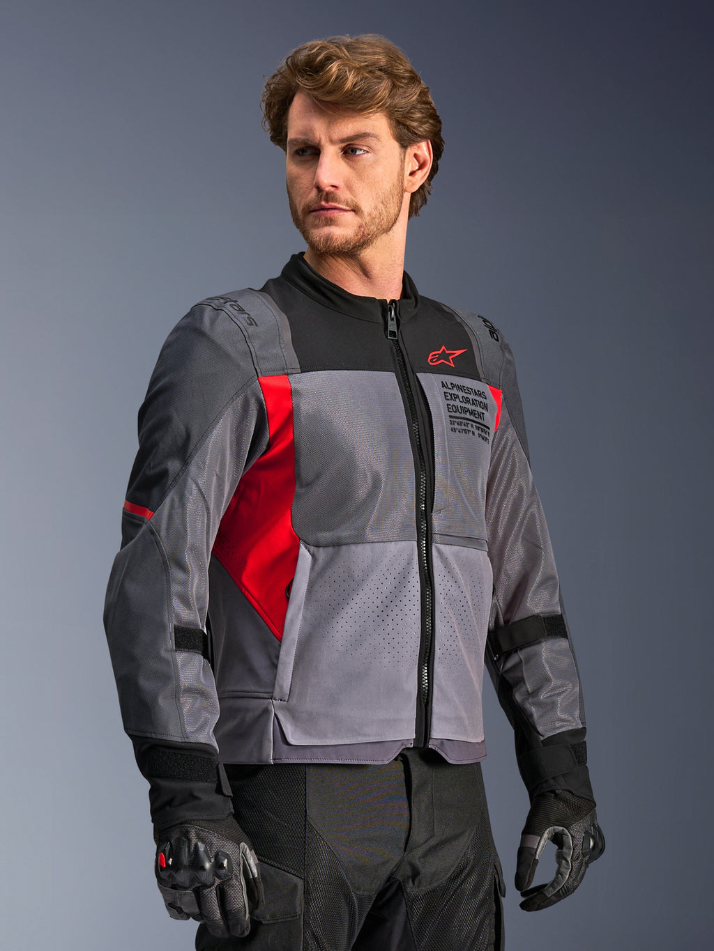Veste Alpinestars St-2 Air, veste de moto, gris foncé et gris anthracite avec accents rouge vif, dotée de larges panneaux de ventilation en maille, de détails perforés au laser et d'un logo étoile rouge, portée par un mannequin en studio, style touring d'aventure moderne